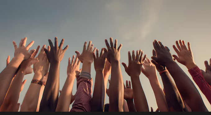 Diverse hands raised together against the sky